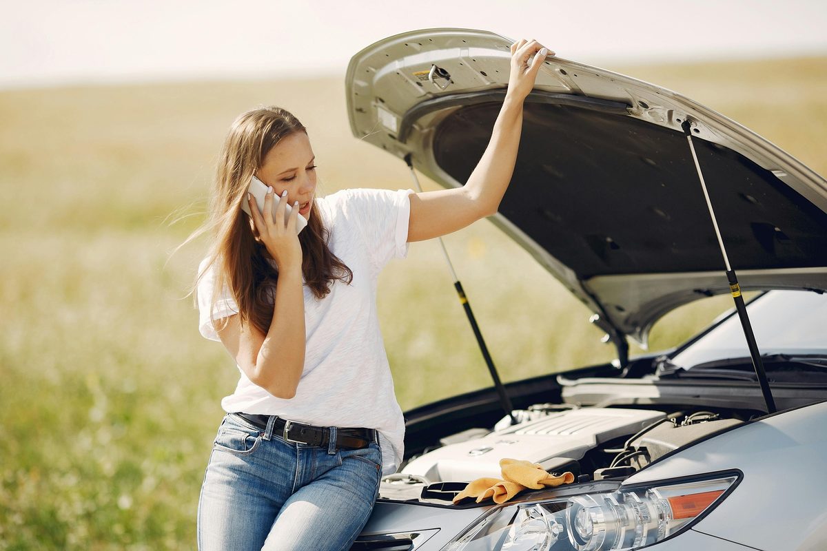 Woman calling for help next to broken down car — a common reason borrowers apply for a Bison Cash emergency loan