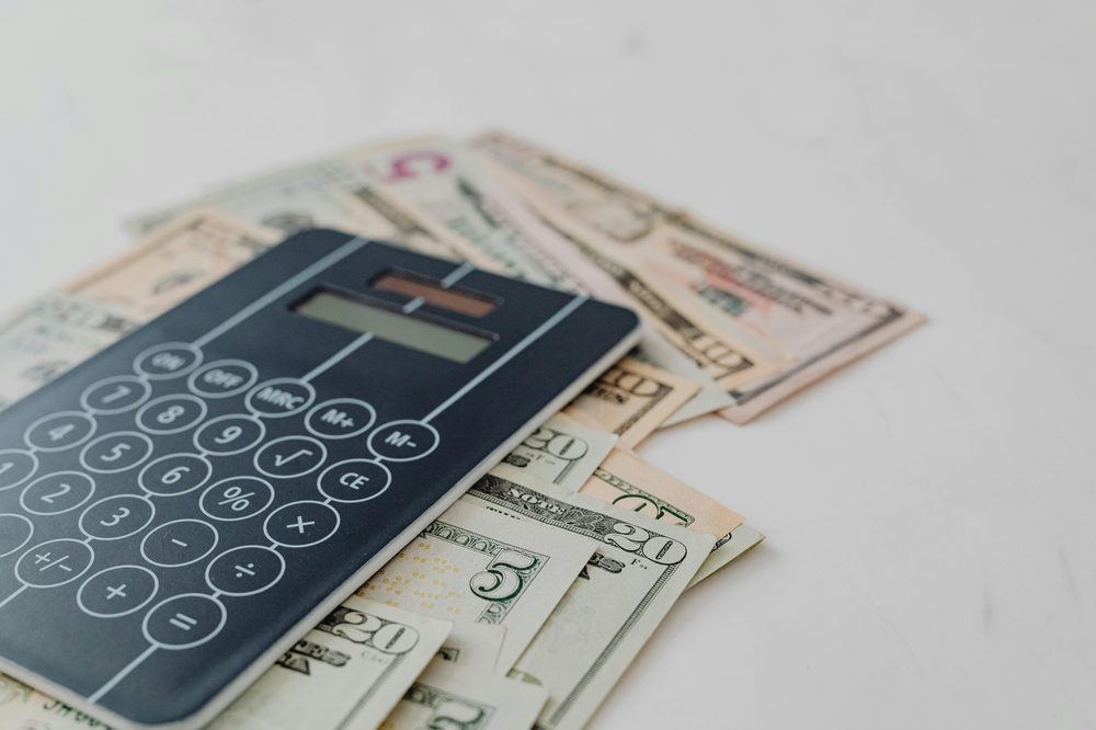 Calculator and US dollar bills — estimating Bison Cash loan monthly payment and total repayment cost